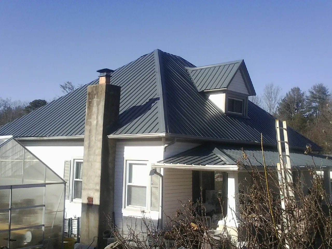 Dark blue standing seam metal roof on a white farmhouse with dormer — Slate & Tile Roof Repair by Roofing Brothers in East Bridgewater