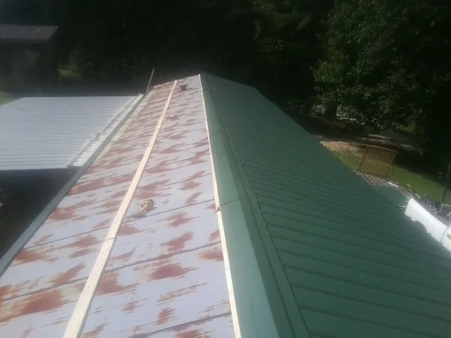 Old rusted panels beside newly installed green metal roofing — Wind Damage Roof Repair by Roofing Brothers in East Bridgewater