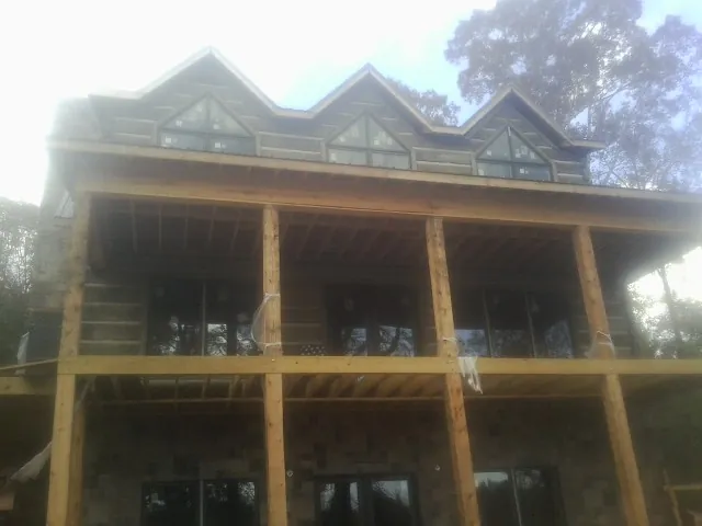 Dormers and porch framing on a large log home under construction — Roof Coating work by our crew in East Bridgewater