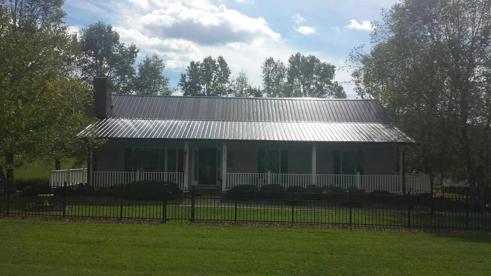 Gray metal roof on a brick ranch with a full width front porch — Gutter Guard Installation work by our crew in East Bridgewater