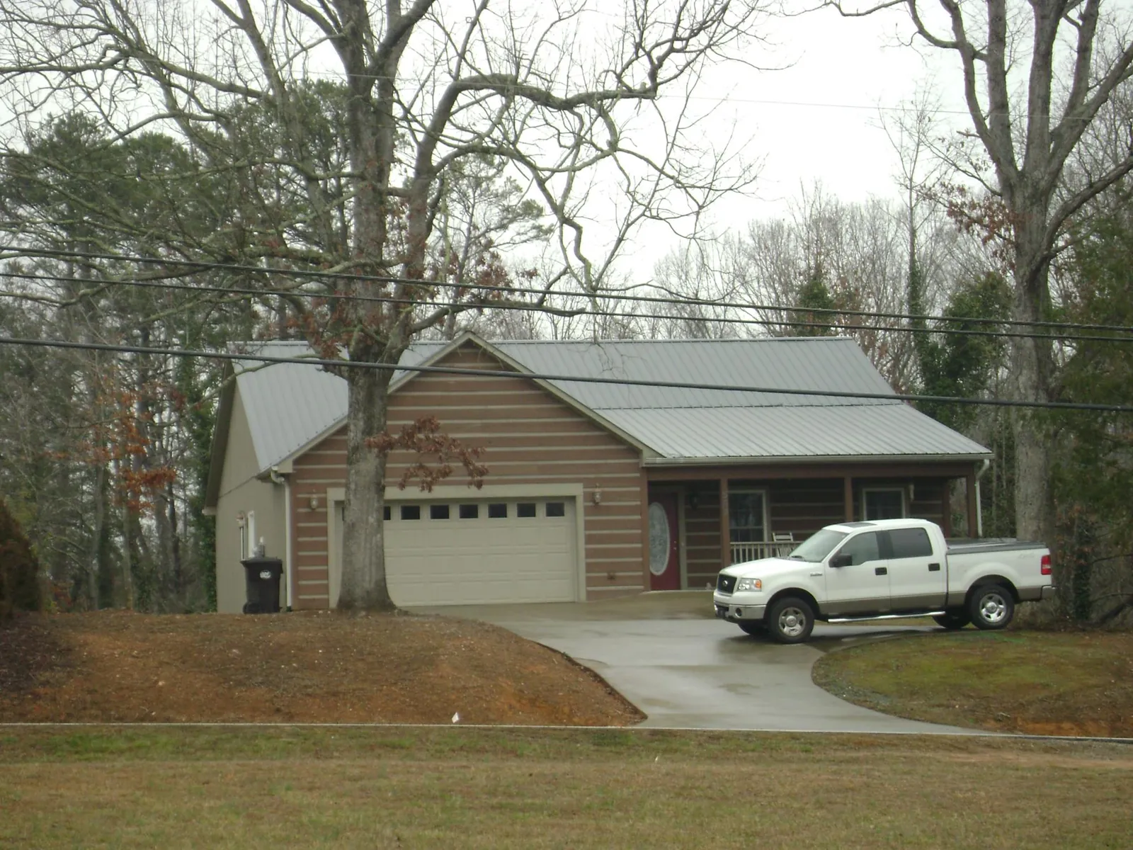 Gray metal roof on a log sided house with an attached two car garage in East Bridgewater