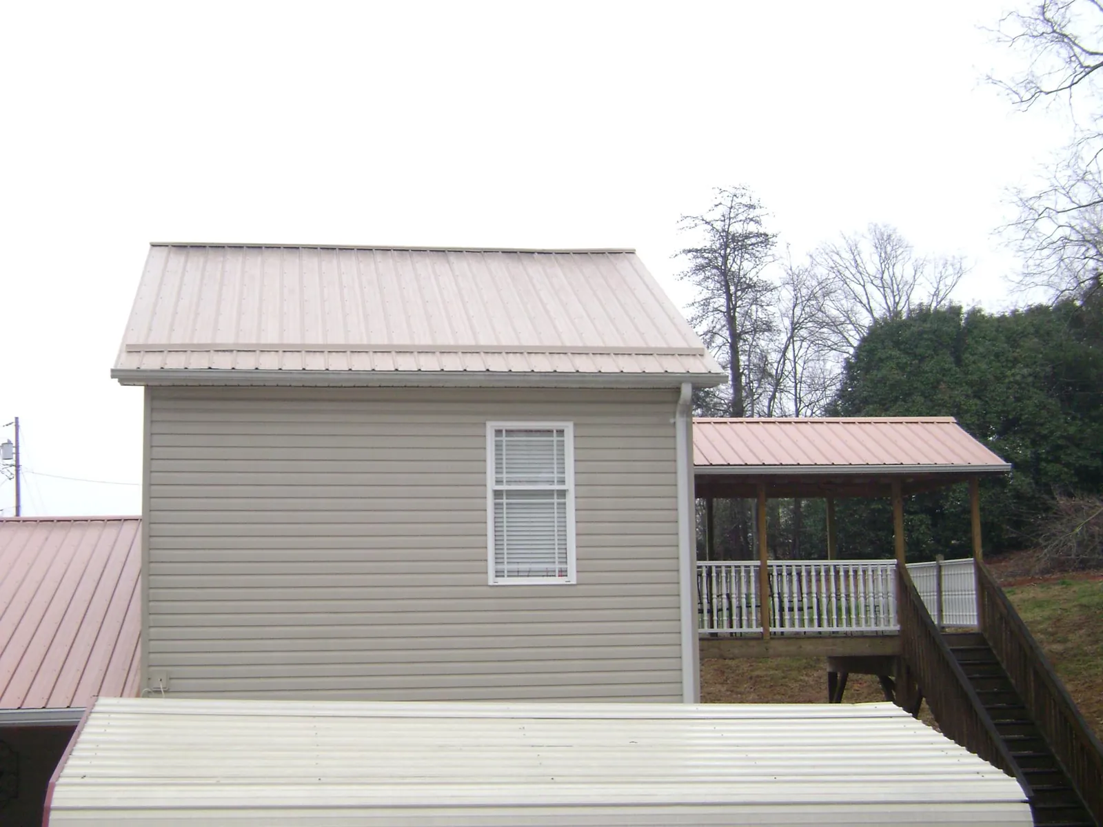 Tan metal roofs on a two story addition and attached porch, from a Roof Replacement job in East Bridgewater