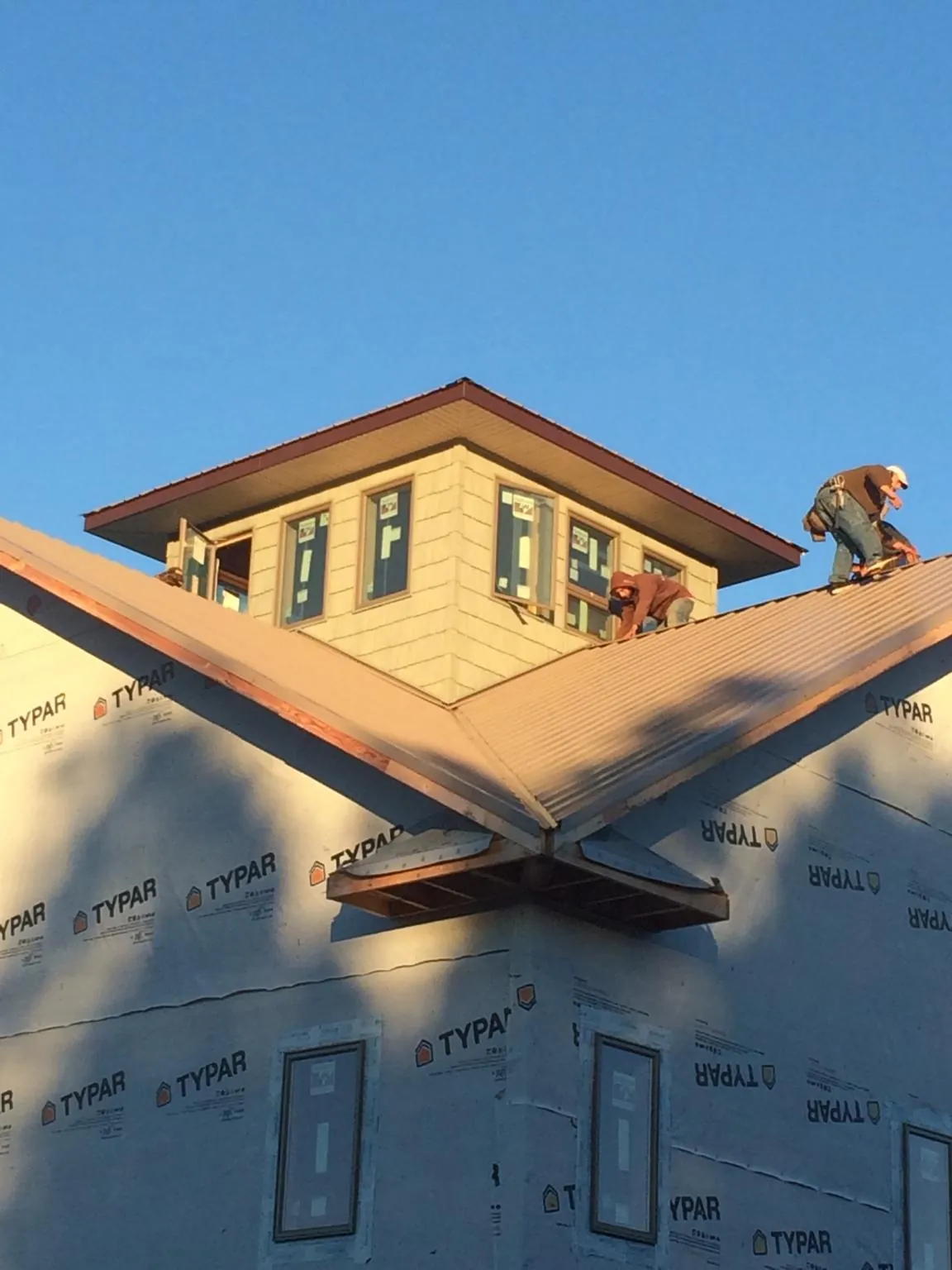 Roofers working around a rooftop cupola on a new metal roof at sunset — Roof Waterproofing in East Bridgewater by Roofing Brothers